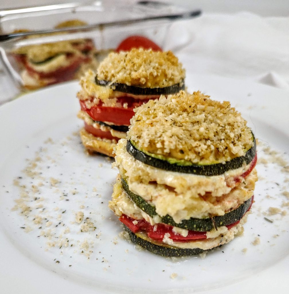 Two baked zucchini tomato lasagna stacks on a white plate.